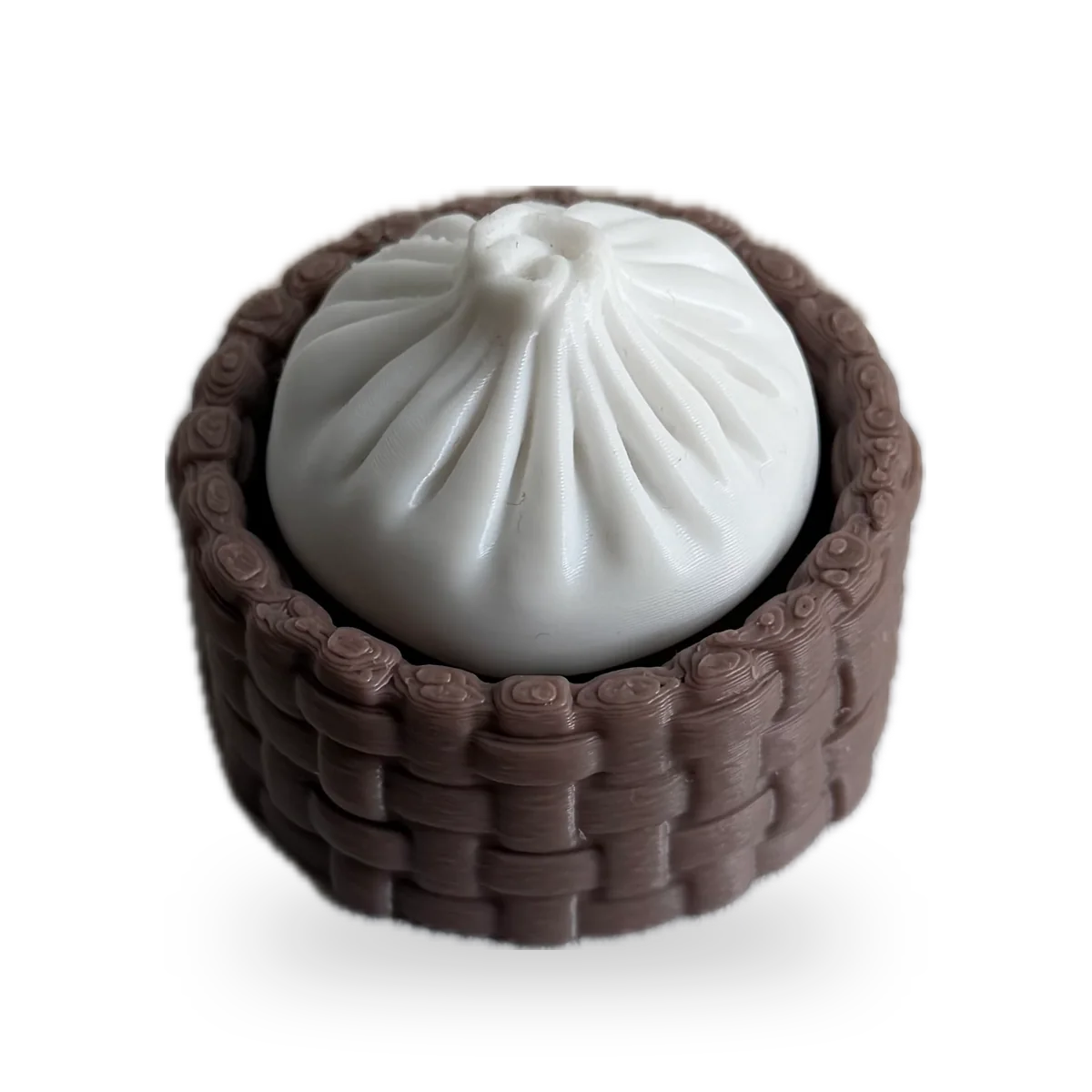 White pork bun clicker in a brown woven steamer basket